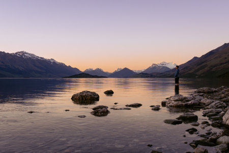 Young man admiring the beuaty in Lake Wakatipu sunset. New Zealand, South Island landscapeの写真素材