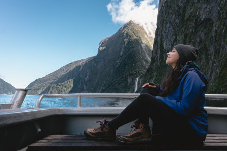 Young woman looking happy sitting on board of a cruise in Milford Sound, New Zealand.の写真素材