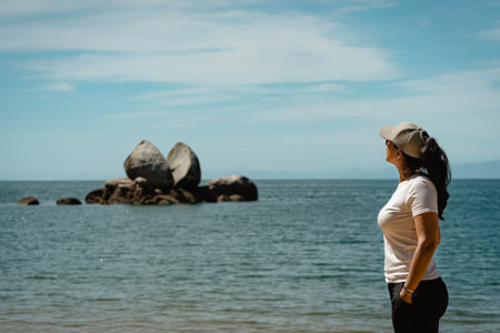 Brunette woman looking at Split Apple Rock. Abel Tasman National Park. New Zealand.の写真素材