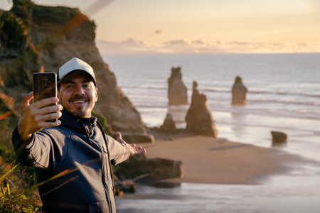 Young man taking a self photo at amazing landscape by the beach. Travel and technology concept.の写真素材