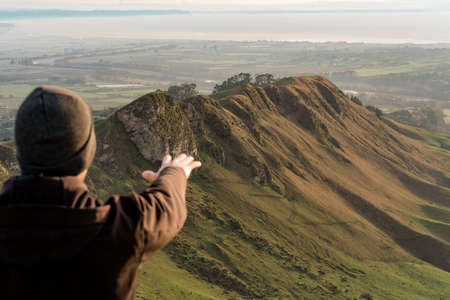 Man at the top of a mountain extending his hand. Landscape photography, travel conceptの写真素材