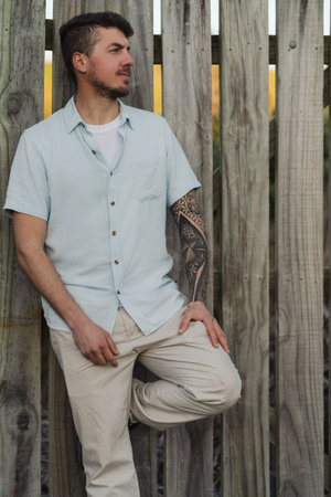 Caucasian tattoo man posing in profile on wooden background.の写真素材