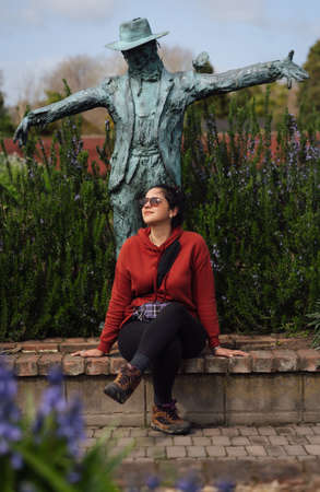 Woman sitting on Hamilton Gardens next to a scarecrow statue. Hamilton, Waikato, New Zealand. September 2020.のeditorial素材