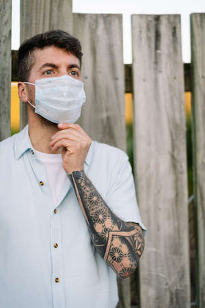 Close up portrait to a young man wearing medical face mask on an open air environment. Covid19 breakout conceptの写真素材