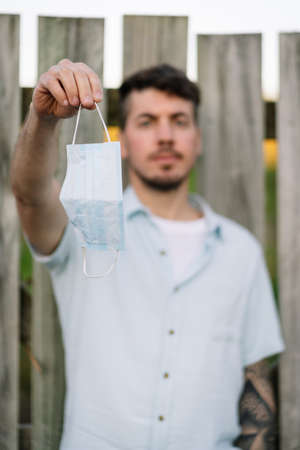 Young man hanging a face mask on his hand on an open air environment.の写真素材