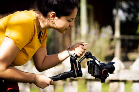 Young hispanic woman holding gimbal while making video outside. Technological conceptの写真素材