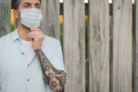 Close up portrait to a young man wearing medical face mask on an open air environment. Covid19 breakout conceptの写真素材