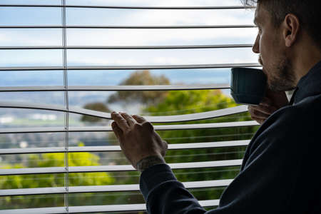 Man drinking coffee and looking through the window at morning. Copy spaceの写真素材