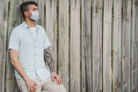 Close up portrait to a young man wearing medical face mask on an open air environment. Covid19 breakout conceptの写真素材