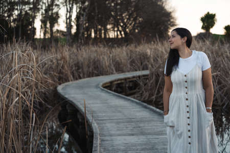 Young hispanic woman on dress walking on wetlands on countryside. Inspirational and Romantic conceptの写真素材