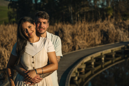 Young couple looking at the camera and posing on natural environment with boardwalk, rushes and a lake. Romanticism conceptの写真素材