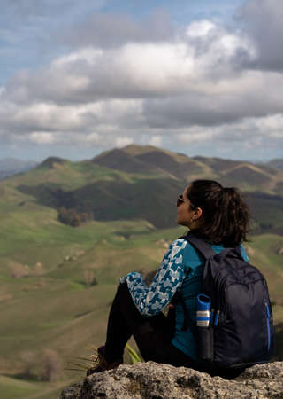 Woman sitting and contemplating the scenery at the peak of a mountainの写真素材