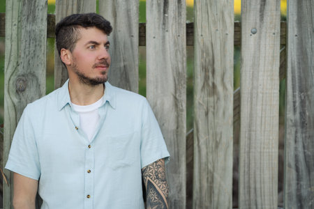Caucasian tattooed man posing in profile on wooden background.Copy space Portrait photographyの写真素材