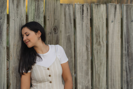 Brunette young woman posing in profile and smiling on wooden background. Portrait photography with bid copy spaceの写真素材