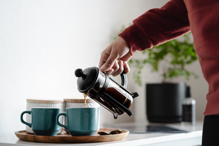 Woman pouring coffee in two coffee cups at morning. Close upの写真素材