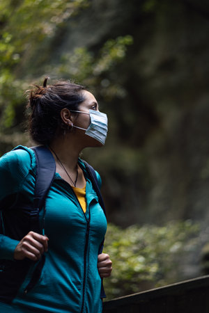 Hispanic woman wearing surgical face mask while walking outdoors.の写真素材