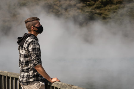 Caucasian young man wearing face mask visiting city with hot springs. Rotorua, New Zealandの写真素材