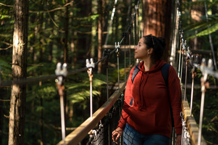 Hispanic woman crossing hanging bridge in the middle of rainforest. Inspirational and travel...