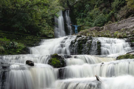 Man opening his arms at the majestic McLean falls. New Zealand, South Island.の写真素材