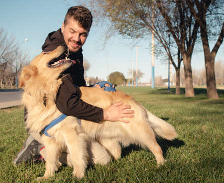 Young man smiling and playing with his dog at the park. Copy spaceの写真素材
