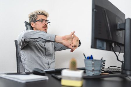 Businessman stretching his hands at the desk of the office. Efficiency at work concept. white backgroundの写真素材