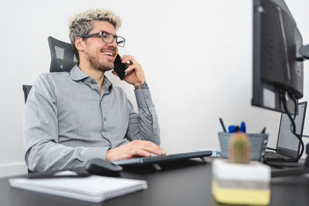 Businessman talking on the phone and smiling while working at the office. Happiness at work conceptの写真素材