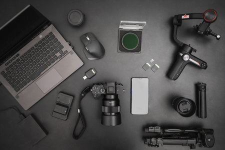 Workplace top view of videographer setting with laptop, camera, gimball, tripod, lens, batteries. top view on dark backgroundの写真素材