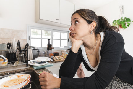 Latin woman worried about her messy kitchen. Close up to her faceの写真素材