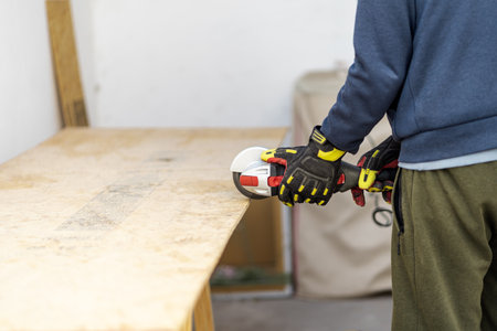 Man cutting piece of wood with electric grinder at home. Outdoor background. unrecognizable personの写真素材