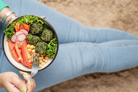 Person eating plant based vegan food in bowl while sitting on the floor at home. close-upの写真素材
