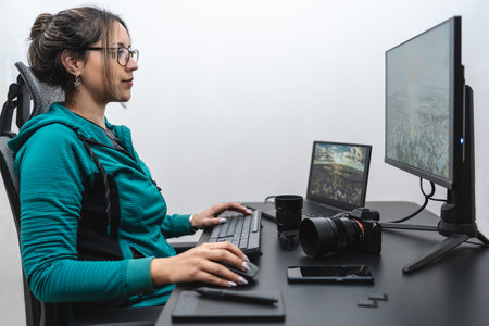 Young Hispanic woman photographer in editing process on her desk. white backgroundの写真素材