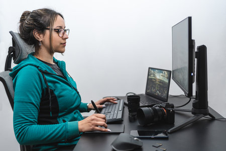 Latin woman photographer editing on her desk with graphic tablet. white backgroundの写真素材