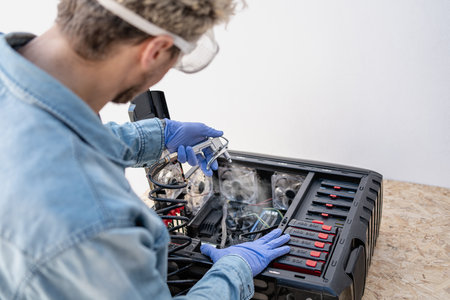 Man with protective glasses and gloves using compressed air gun for blowing inside of computer. Close up. copy-spaceの写真素材