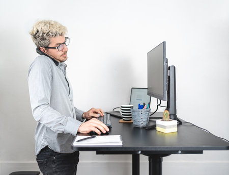 Man talking on the phone while working at the office in modern standing desk. white backgroundの写真素材