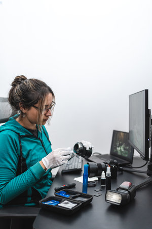 Woman photographer cleaning her lens and camera with cleaning kit and wearing gloves. portrait photoの写真素材