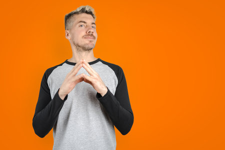 Young handsome blonde man smiling with thumbs up in casual clothing. Isolated colorful orange backgroundの写真素材