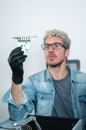 Caucasian man holding sound card for desktop computers. Selective focus, Vertical photoの写真素材