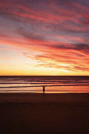 Person with open arms at the beach during sunrise. portrait photographyの写真素材