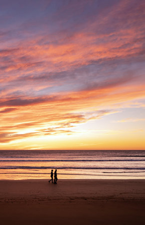 Couple walking along the beach at dramatic sunrise. portrait photographyの写真素材