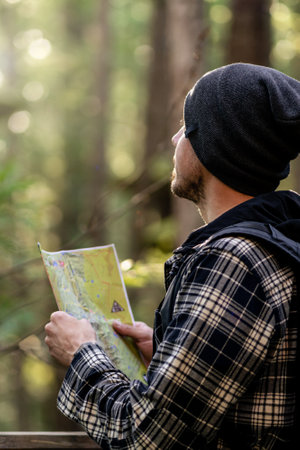 Young man lost in the wild of the rainforest holding map on his hand. portrait photographyの写真素材