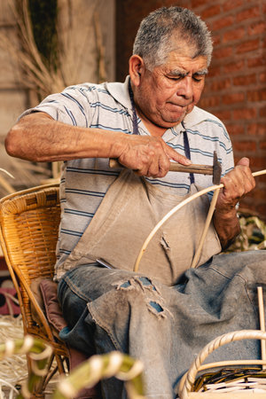 Old man using hammer for making wicker baskets at his workshop. portrait photographyの素材 [FY310196385710]