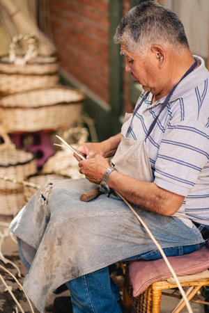 Latin American craftsman cutting wicker willow cane and knife for making wicker baskets. portrait photographyの写真素材
