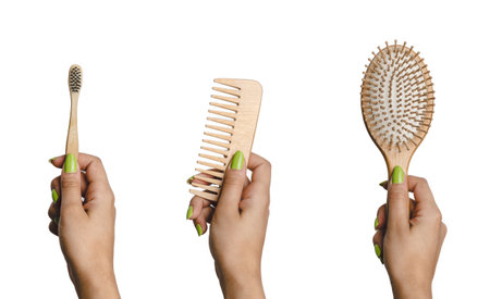 Woman hand holding eco friendly set of hairbrush, comb and toothbrush made of bamboo. Sustainability and eco friendly bathroom accessories. White isolated studio shotの写真素材