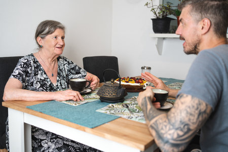 Old woman sharing tea time with her adult son at home. selective focusの写真素材