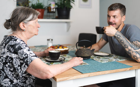 Senior lady mother and her are spending time together while having tea and chatting at home. Supporting the eldest conceptの写真素材