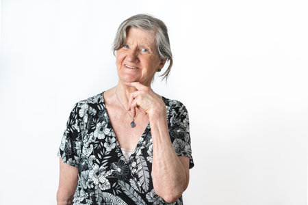 Cute portrait of gray-haired old lady posing and looking at camera over isolated white background. Copy space on right sideの写真素材