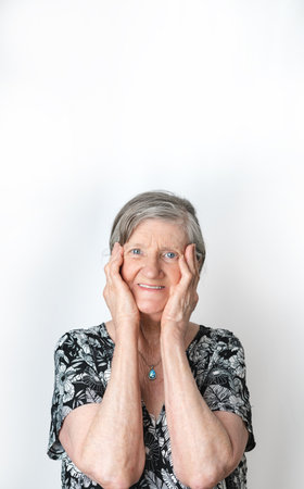 Senior woman making cute expression while smiling and looking at camera. White isolated camera. portrait photographyの写真素材