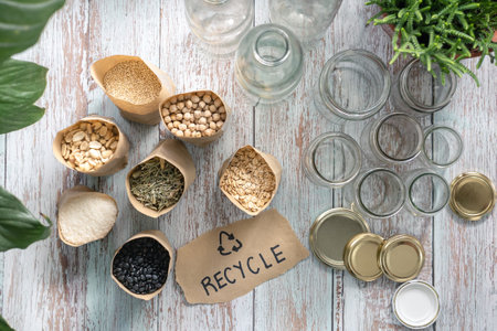 "Recycle" written on a paper above a wooden table with bulk food and recycled glass jars in the kitchen table. Overhead top view shot. Zero waste and Recycling conceptの写真素材