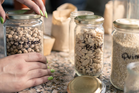 Close up of woman using recycled glass jars for bulk food such as chickpeas, peanuts, beans, etc. Reduce, reuse, recycle concept.の写真素材
