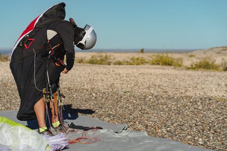 Professional paraglider in flight suit with helmet getting ready for flying. Copy space on right side for textの写真素材